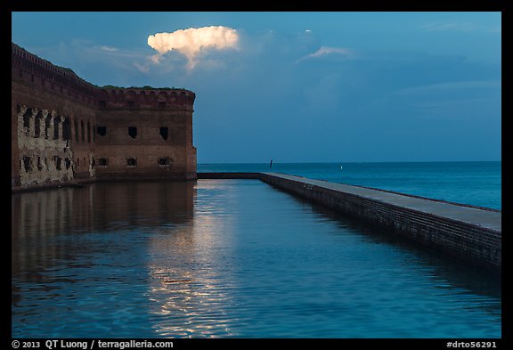 Moat, fort, bright cloud at dawn. Dry Tortugas National Park, Florida, USA.
