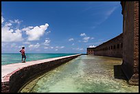 Park visitor looking, Fort Jefferson moat and seawall. Dry Tortugas National Park, Florida, USA. (color)