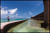 Park visitor looking, Fort Jefferson moat and seawall. Dry Tortugas National Park ( color)