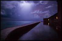 Fort Jefferson seawall at night with sky lit by thunderstorm. Dry Tortugas National Park, Florida, USA. (color)