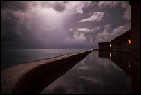 Fort Jefferson seawall at night with sky lit by tropical storm. Dry Tortugas National Park, Florida, USA.