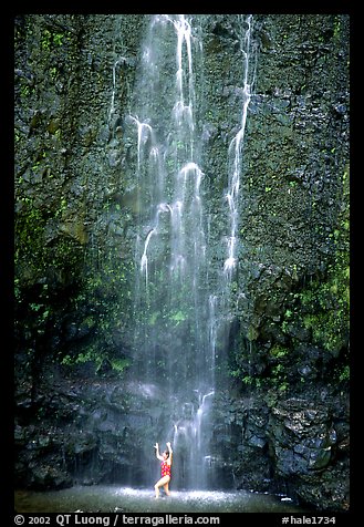 Tourist refreshes herself at the base of Waimoku Falls. Haleakala National Park, Hawaii, USA.