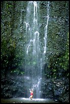 Tourist refreshes herself at the base of Waimoku Falls. Haleakala National Park, Hawaii, USA.