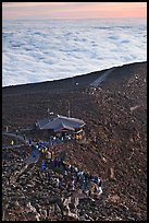 People gather to watch sunrise above sea of clouds. Haleakala National Park, Hawaii, USA.