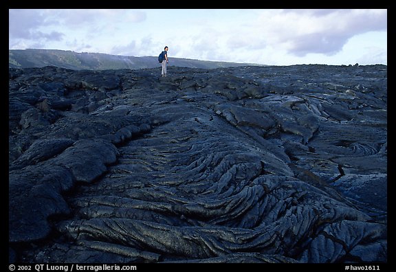 Hiker on hardened lava flow at the end of Chain of Craters road. Hawaii Volcanoes National Park, Hawaii, USA.