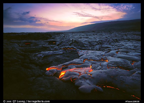Volcanic landscape with molten lava flow and red spots at sunset. Hawaii Volcanoes National Park, Hawaii, USA.