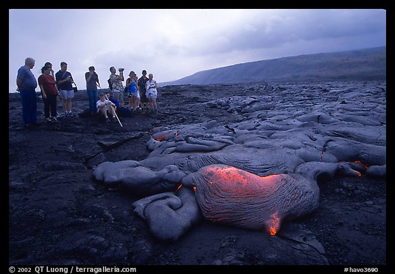 Hikers observe a live lava flow at close distance. Hawaii Volcanoes National Park, Hawaii, USA.