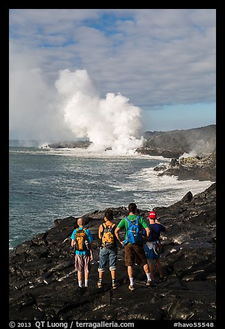 Hikers looking at molten lava and coastal volcanic steam cloud. Hawaii Volcanoes National Park, Hawaii, USA.