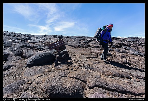 Hiker descending from Mauna Loa summit next to sign. Hawaii Volcanoes National Park, Hawaii, USA.