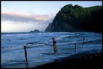 Hawaiian woman piling a stone on a stick as a gesture of reverence, Polulu Beach. Big Island, Hawaii, USA ( color)