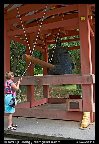 Tourist rings the sacred bell before entering Byodo-In temple. Oahu island, Hawaii, USA