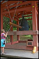 Tourist rings the sacred bell before entering Byodo-In temple. Oahu island, Hawaii, USA