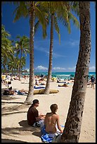 Couple under palm trees on Waikiki beach. Waikiki, Honolulu, Oahu island, Hawaii, USA