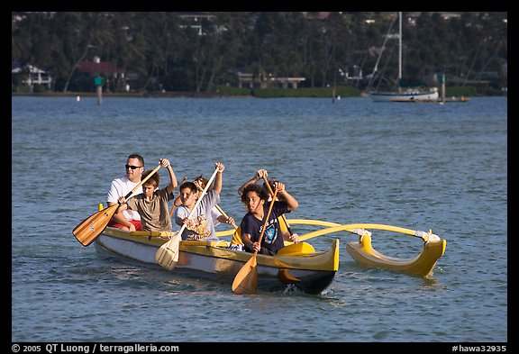 Boys paddling an outrigger canoe, Maunalua Bay, late afternoon. Oahu island, Hawaii, USA