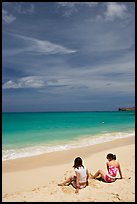 Young women sitting on Waimanalo Beach. Oahu island, Hawaii, USA