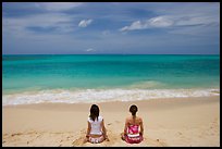 Young women facing ocean in meditative pose on Waimanalo Beach. Oahu island, Hawaii, USA