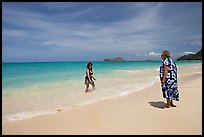 Two women, the older in hawaiian dress, on Waimanalo Beach. Oahu island, Hawaii, USA