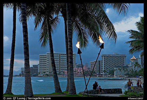 Waterfront at dusk with bare flame lamps. Waikiki, Honolulu, Oahu island, Hawaii, USA (color)