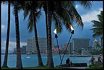 Waterfront at dusk with bare flame lamps. Waikiki, Honolulu, Oahu island, Hawaii, USA ( color)