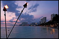 Bare flame torches and skyline at sunset. Waikiki, Honolulu, Oahu island, Hawaii, USA