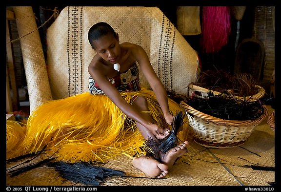 Fiji woman tying together leaves with her feet. Polynesian Cultural Center, Oahu island, Hawaii, USA (color)