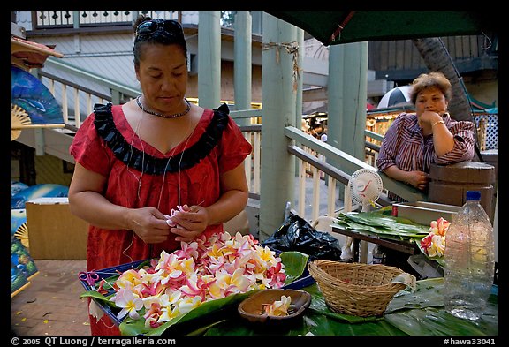 Woman preparing a fresh flower lei, with another woman looking, International Marketplace. Waikiki, Honolulu, Oahu island, Hawaii, USA