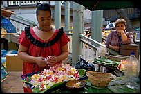 Woman preparing a fresh flower lei, with another woman looking, International Marketplace. Waikiki, Honolulu, Oahu island, Hawaii, USA (color)