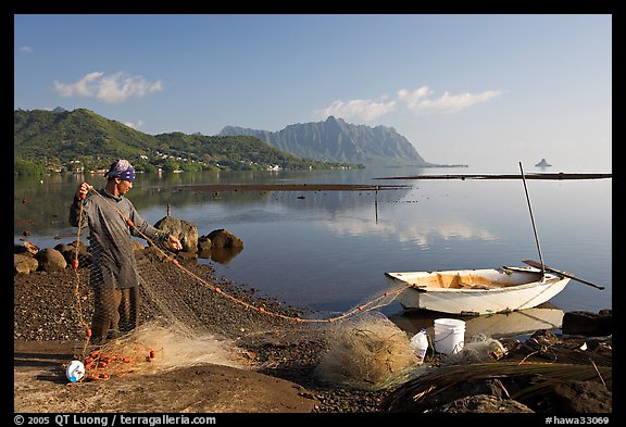 Fisherman pulling out net out of small baot, Kaneohe Bay, morning. Oahu island, Hawaii, USA