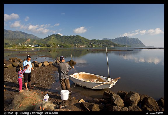 Fisherman and family pulling out net out of small baot, Kaneohe Bay, morning. Oahu island, Hawaii, USA (color)