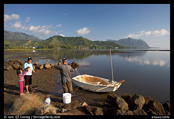 Fisherman and family pulling out net out of small baot, Kaneohe Bay, morning. Oahu island, Hawaii, USA