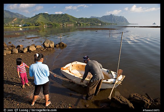 Fisherman and family pulling out net out of small baot, Kaneohe Bay, morning. Oahu island, Hawaii, USA