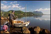 Fisherman pulling out fish out a net, with girl looking, Kaneohe Bay, morning. Oahu island, Hawaii, USA (color)