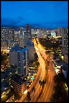 Boulevard and high rise buildings at dusk. Waikiki, Honolulu, Oahu island, Hawaii, USA