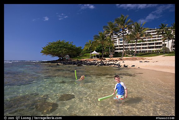 Children on Puu Poa Beach and Princeville Hotel. Kauai island, Hawaii, USA