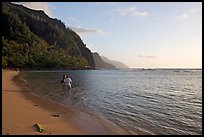 Couple standing in water looking at the Na Pali Coast, Kee Beach, late afternoon. Kauai island, Hawaii, USA ( color)