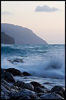 Boulders, waves, and Na Pali cliffs, sunset. Kauai island, Hawaii, USA