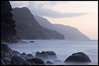 Boulders, surf, and Na Pali cliffs, sunset. Kauai island, Hawaii, USA ( color)