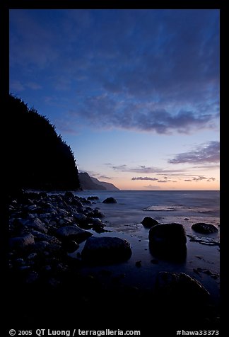 Boulders, surf, and Na Pali cliffs, dusk. North shore, Kauai island, Hawaii, USA (color)