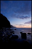 Boulders, surf, and Na Pali cliffs, dusk. North shore, Kauai island, Hawaii, USA ( color)