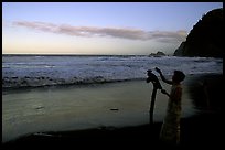 Hawaiian woman piles a stone on a stick as a traditional gesture of reverence, Polulu Beach. Big Island, Hawaii, USA (color)