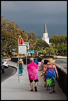Beachgoers walking past ironman triathlon sign, Kailua-Kona. Hawaii, USA (color)