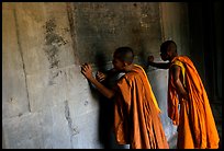 Two buddhist monks examine  bas-reliefs in Angkor Wat. Angkor, Cambodia (color)