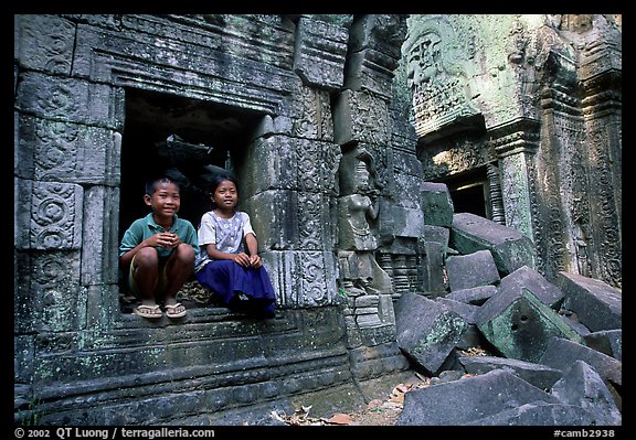 Boy and girl sit at window in Ta Prom. Angkor, Cambodia