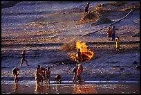 Children bathe in the river and dry out near a fire in a small hamlet. Mekong river, Laos (color)