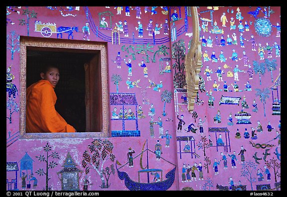 Buddhist novice monk sits at window of shrine, Wat Xieng Thong. Luang Prabang, Laos