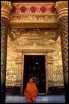 Buddhist novice monk sits at door of Wat Mai Suwannaphumaham. Luang Prabang, Laos ( color)