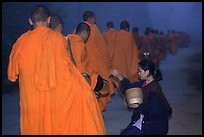 Woman gives alm during morning procession of buddhist monks. Luang Prabang, Laos (color)