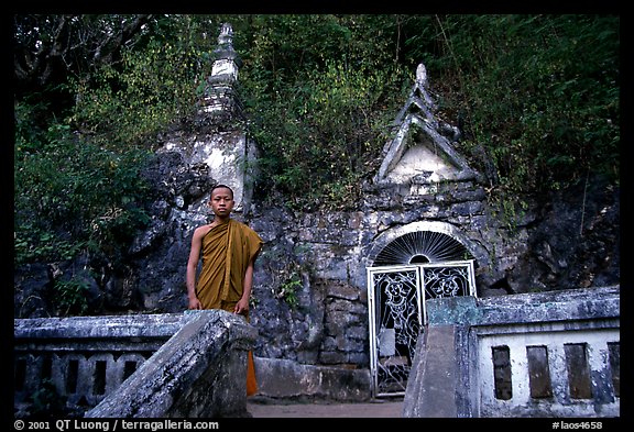 Novice Buddhist monk at entrance of cave, Pak Ou. Laos (color)