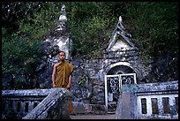 Novice Buddhist monk at entrance of cave, Pak Ou. Laos (color)