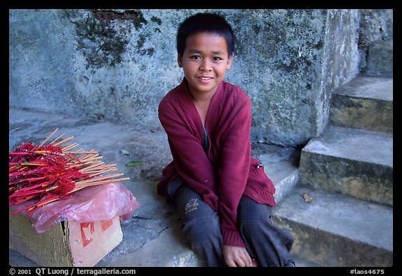 Boy sells incence sticks at the entrance of a shrine, Pak Ou. Laos